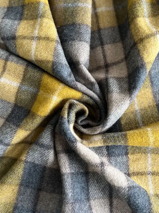 Buchanan Natural Recycled Wool Blanket, a brown and yellow blanket curled up. 