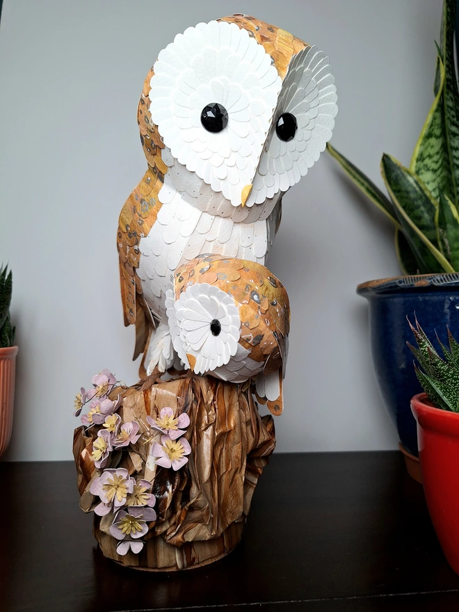 Handmade mother and baby sculpture featuring barn owls on a tree stump adorned with paper flowers