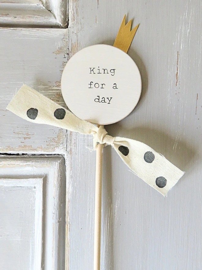 wooden circle shaped cake topper with hand painted message, gold painted crown detail and custom ribbon