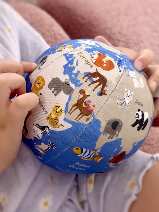 First globe soft toy in the hands of a little girl. She is pointing at an elephant in Africa