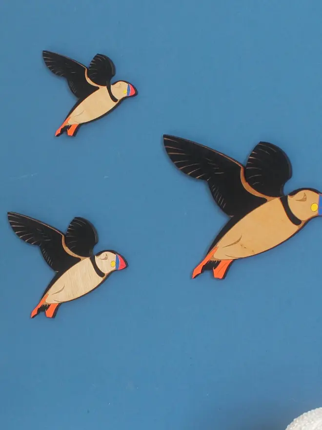 Flying Wooden Wall Puffins (Set Of 3), group of flying wooden puffins hanging on wall. 