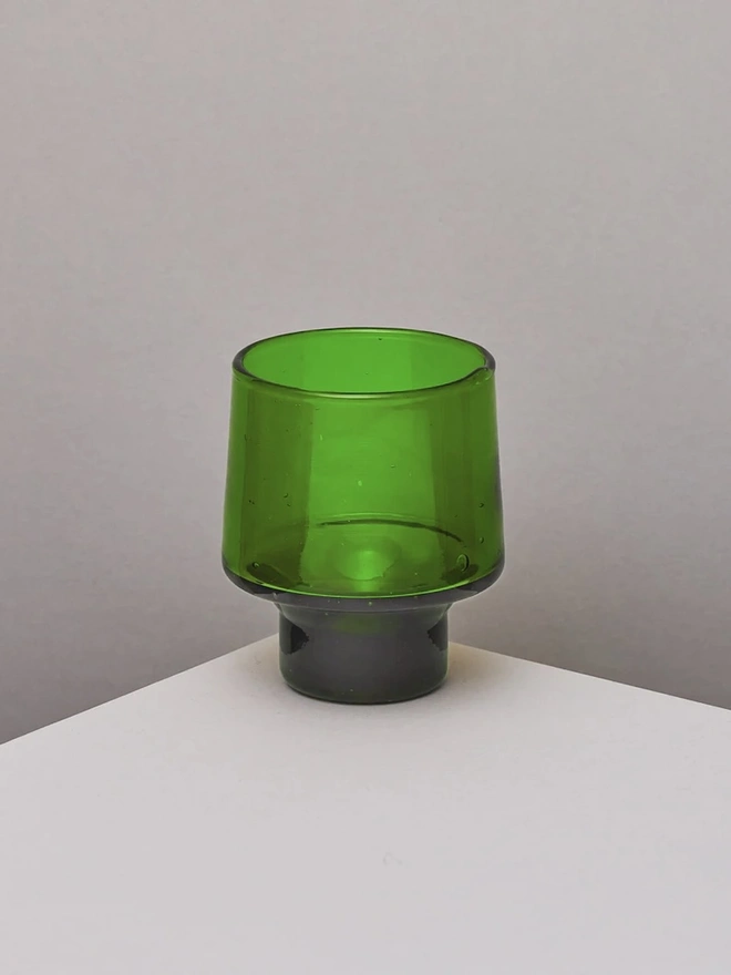 Low Wine Glasses (Set Of 1 Or 4), a green wine glass sitting on a plain counter top against a white backdrop. 