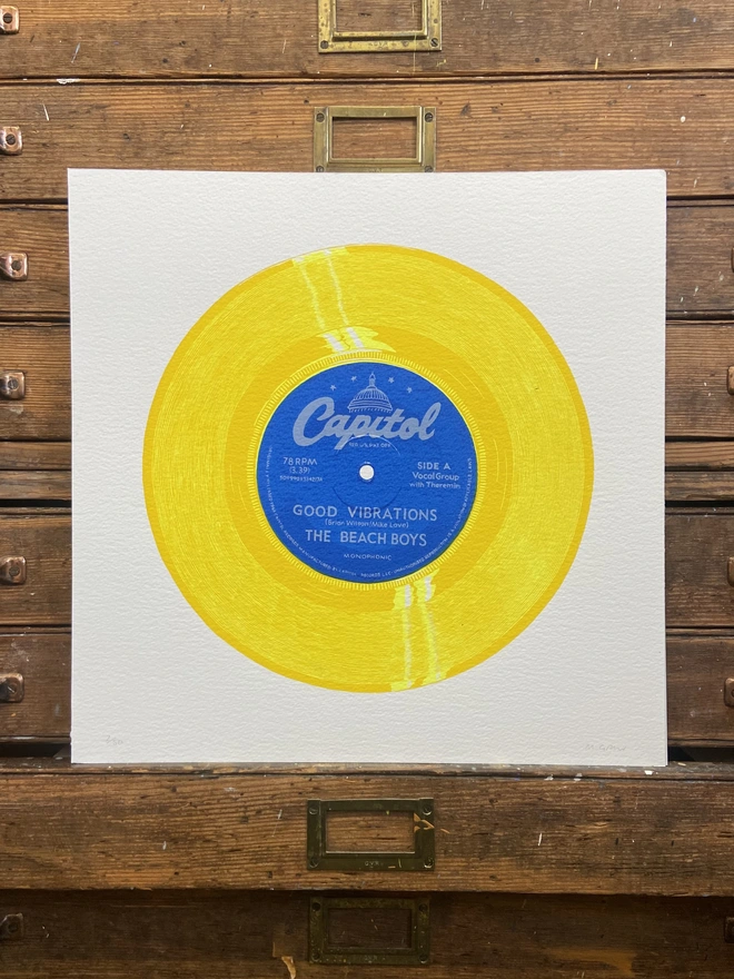 The Beach Boys Good Vibrations yellow Vinyl Screen Print leaning on a shelf