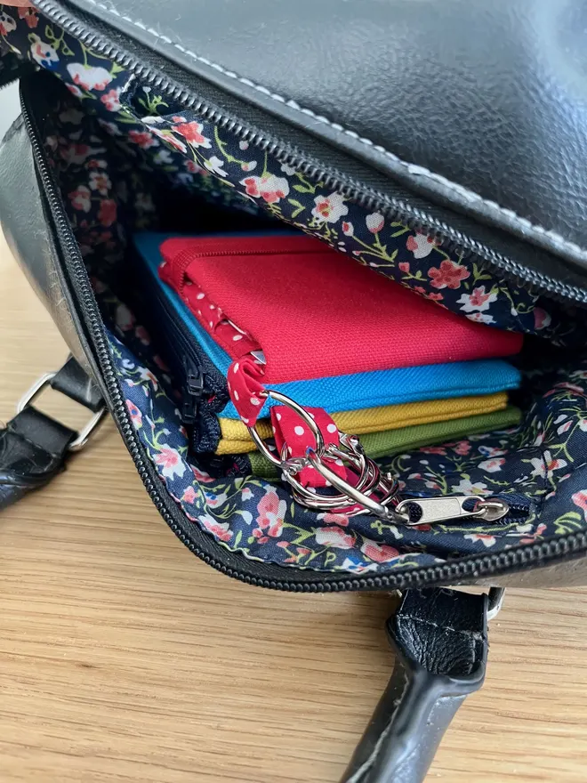 Set of 3 colourful coin purses and card wallet inside a black handbag.