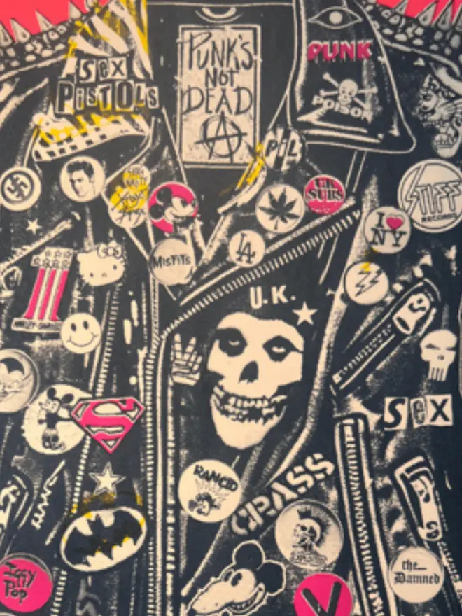 A punk leather jacket decorated with music band patches against a neon pink background.