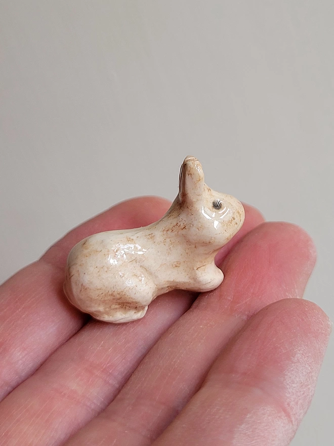 little ceramic beige bunny figurine held in a hand