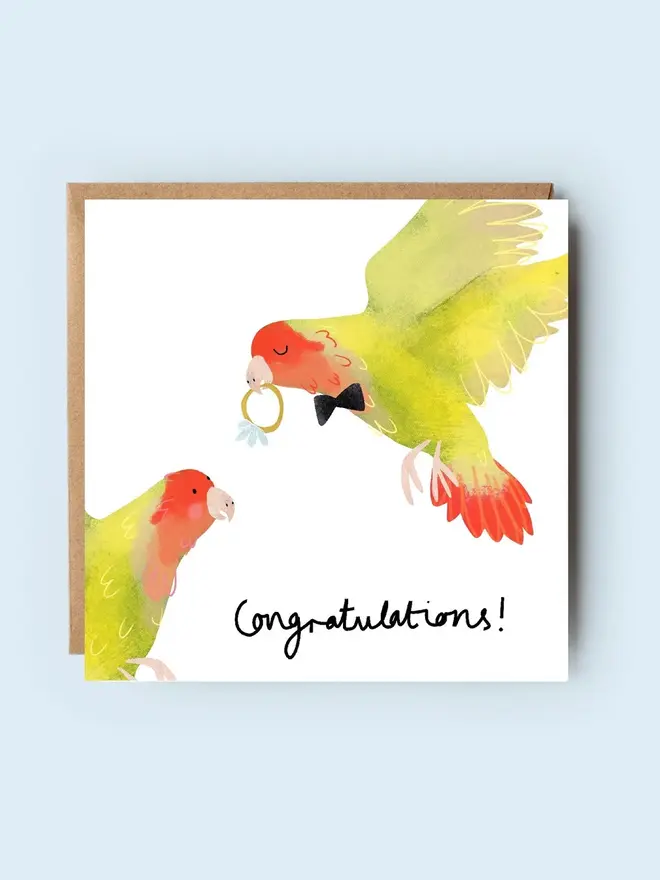 'lovebirds' illustrated engagement card. card photographed against plain blue background.