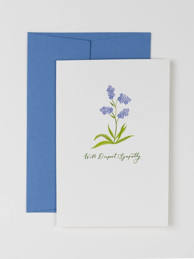 An illustration of a delicate Forget-me-not flower on a white background. There is hand-written cursive text underneath the flower that reads "With Deepest Sympathy"