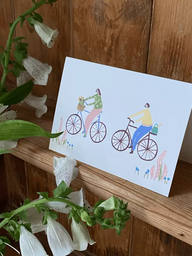 girl and boy on a bike greetings card.