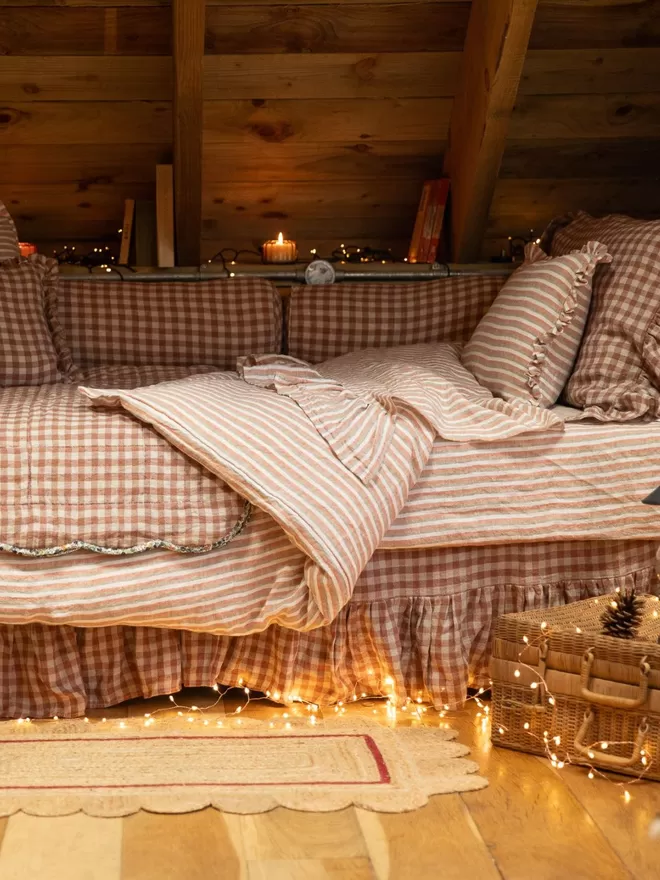 Linen Bolster Cushion 'Rose Gingham' cushion is displayed on a bed