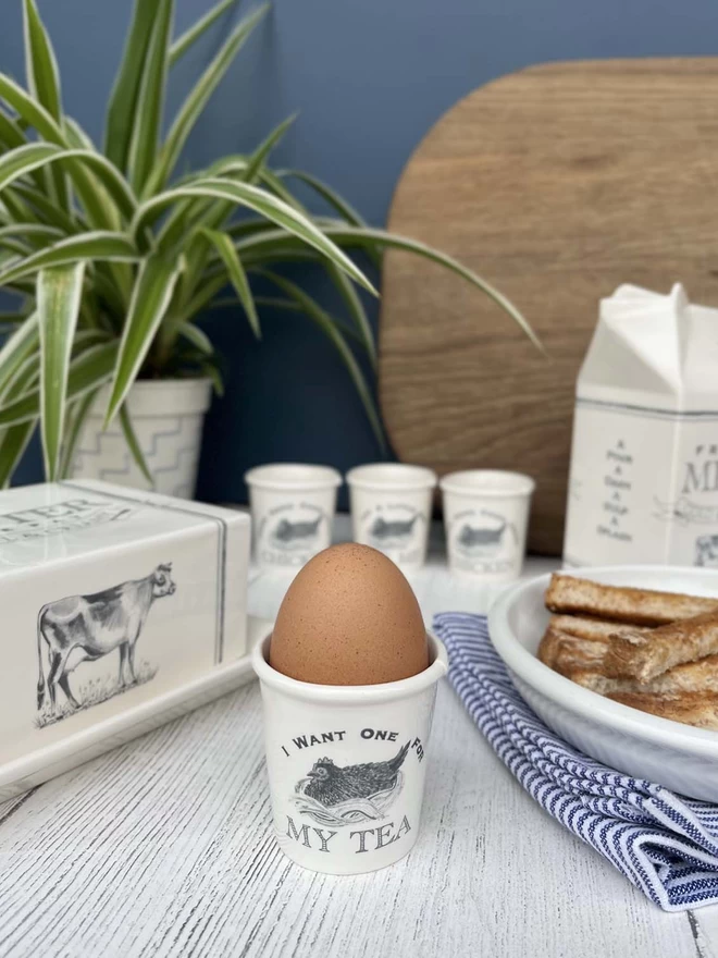 Handmade ceramic egg cups stands with matching butter dish, sugar pot, milk and cream cartons.