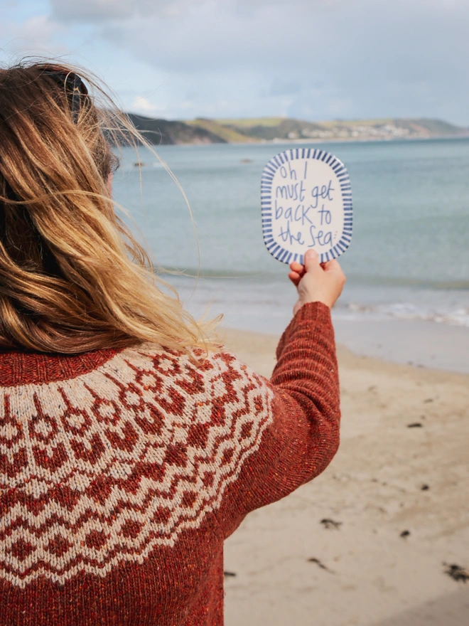 laura lane holding the plaque by the sea in cornwall