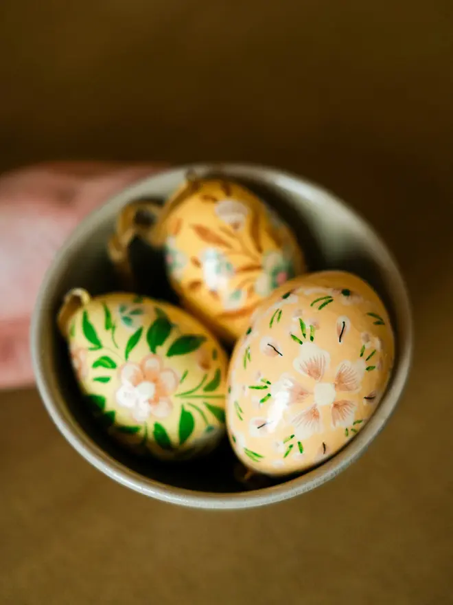 Group shot of hand painted decorative eggs in a bowl on a wooden table