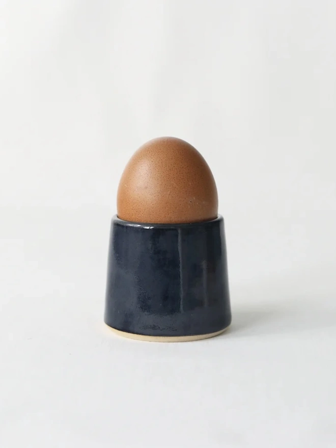 Classic Handmade Egg Cup, a ceramic egg cup sitting on a plain surface against a white backdrop. 
