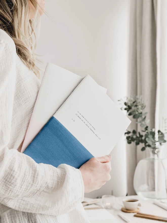 Holding a an A4 blue and white personalised notebook under arm