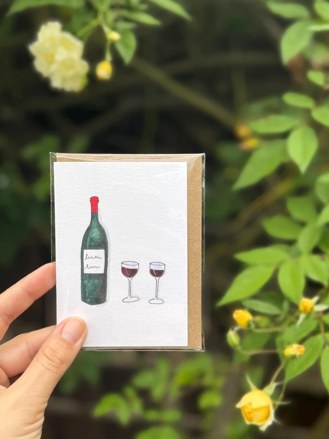 red wine illustrated mini card. card photographed against rosebush backdrop.