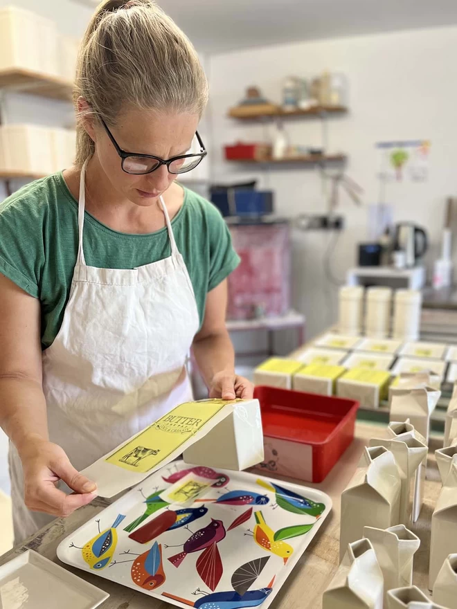 A transfer is wrapped around a lid, once fired the yellow will burn away to reveal the decoration.