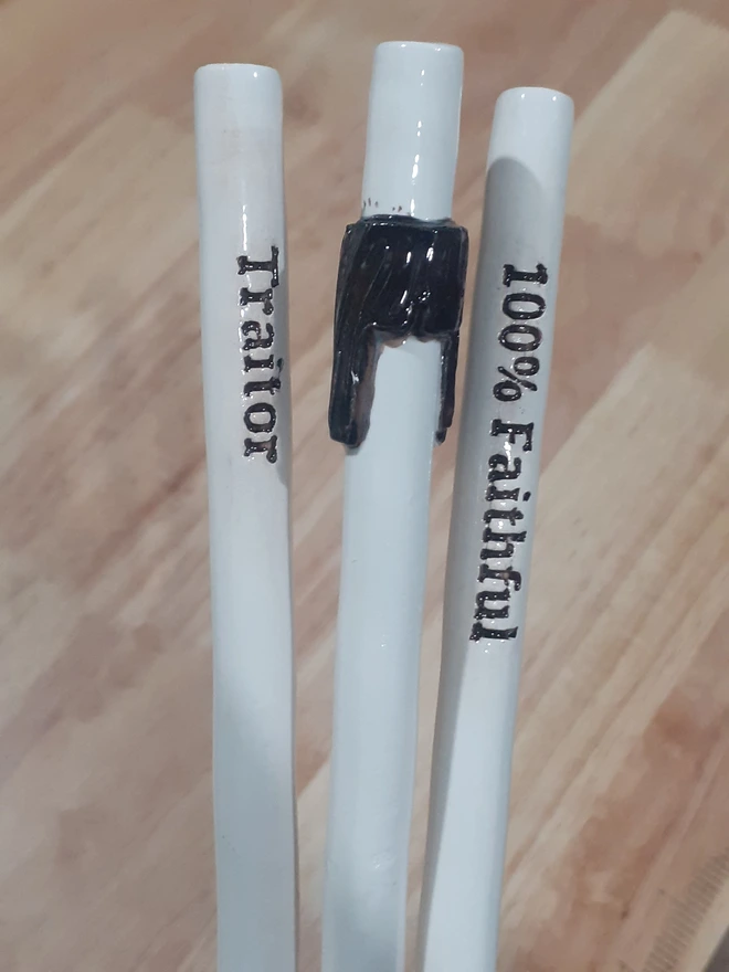 Minimalist product photo of The Traitors–inspired ceramic drinking straw set, highlighting hand-applied lettering, glossy glaze, and subtle handmade variations.