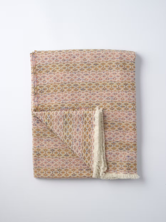 cairmeal lambswool blanket. a pink and brown blanket photographed folded on a white background.