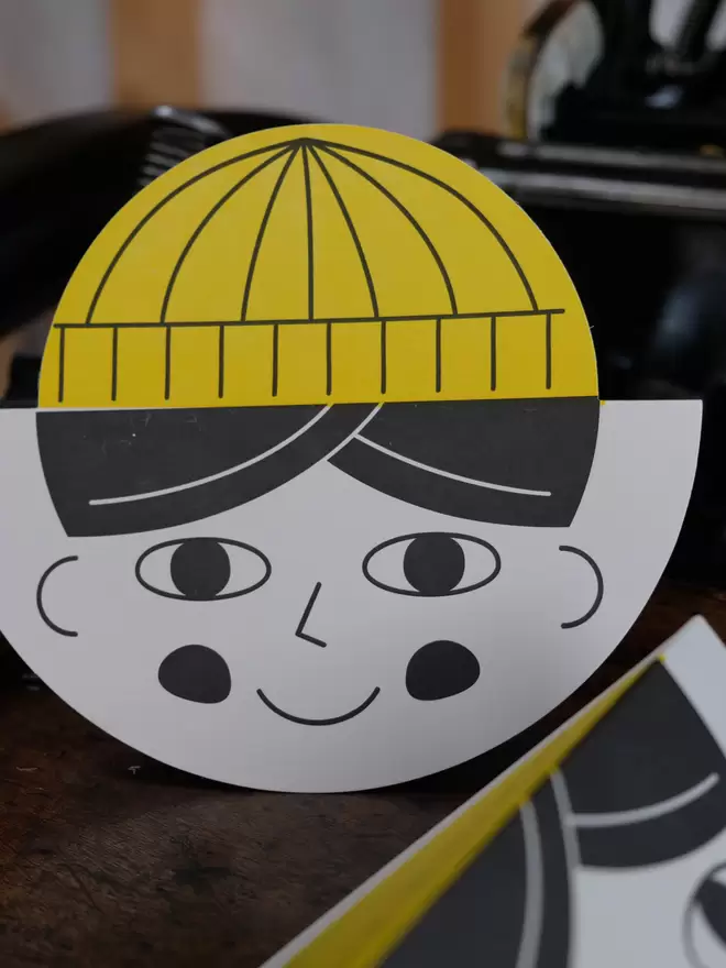 Fun, illustrative childs face card with yellow hat.