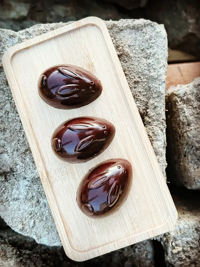 three chocolate bunnies on wooden platform