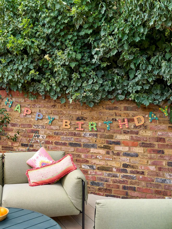 Biright Happy Birthday Garland - hanging outdoors againts a brick wall 