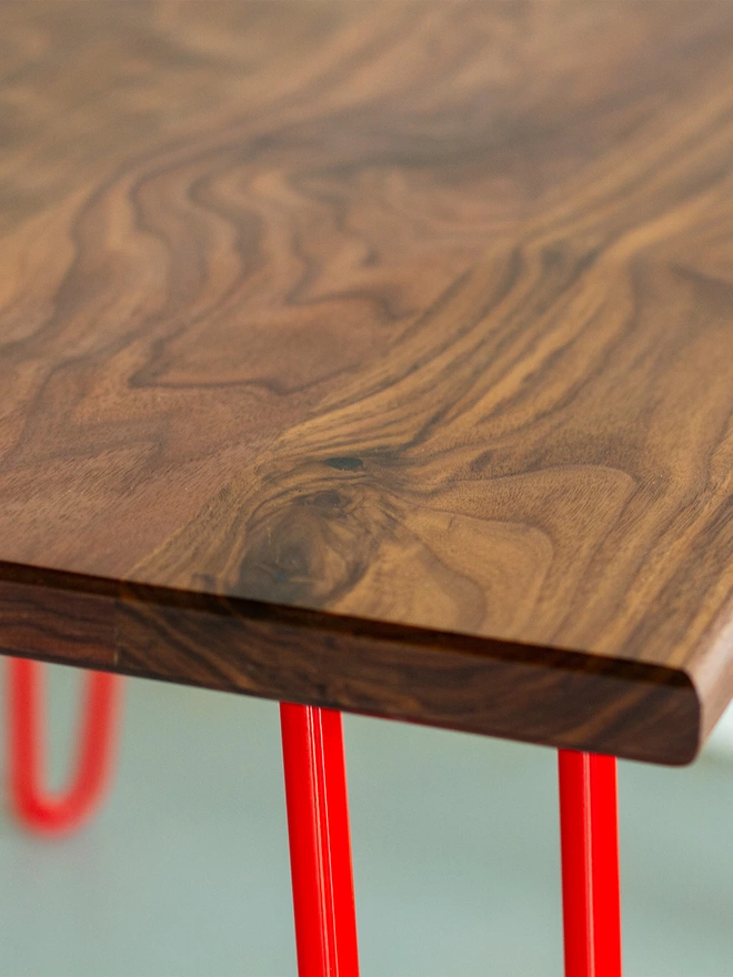corner view of a hairpin leg table with walnut top and red legs