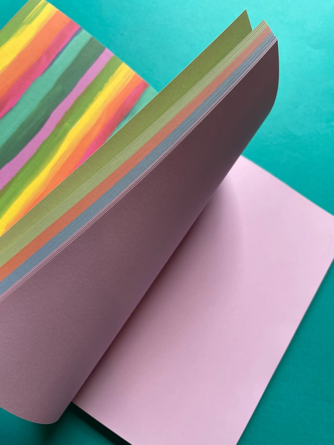 Inside view of the A5 notebook. Showing the rainbow paper sections of the notebook, including a minty green, and coral