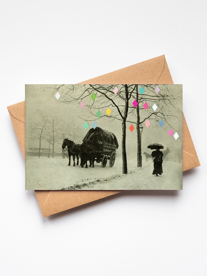 A victorian winter street scene depicting a woman holding an umbrella and a horse and carriage. Trees are draped with fairy lights.