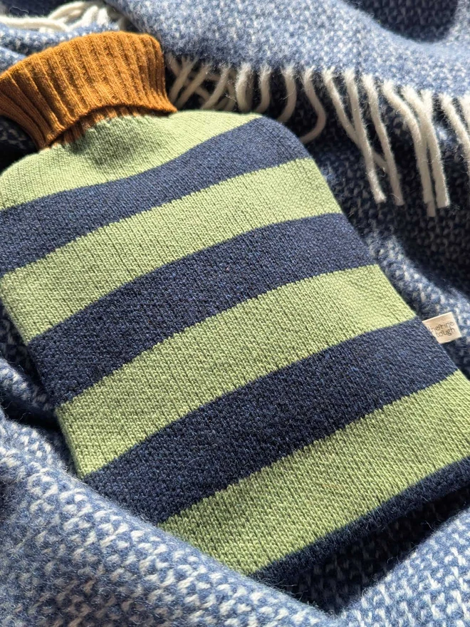 COLOURFUL HOT WATER BOTTLE COVER DISPLAYED ON A ON A BLANKET