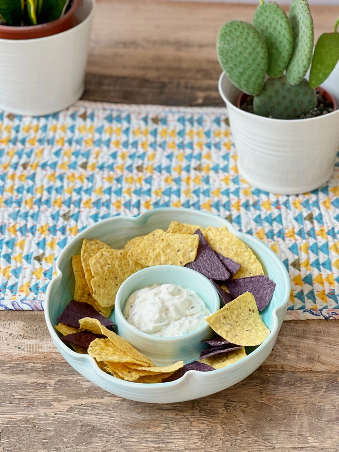 flower shaped chip and dip bowl on table with tortilla chips and dip