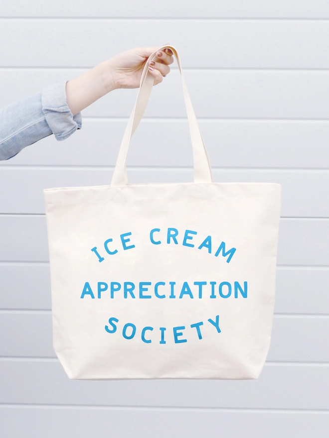 a hand holding out a large natural canvas tote bag with the words ice cream appreciation society