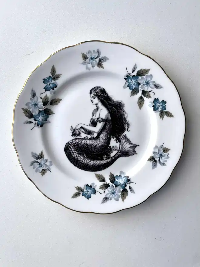 a vintage plate with a really ornate border in the centre is printed a vintage illustration of a mermaid