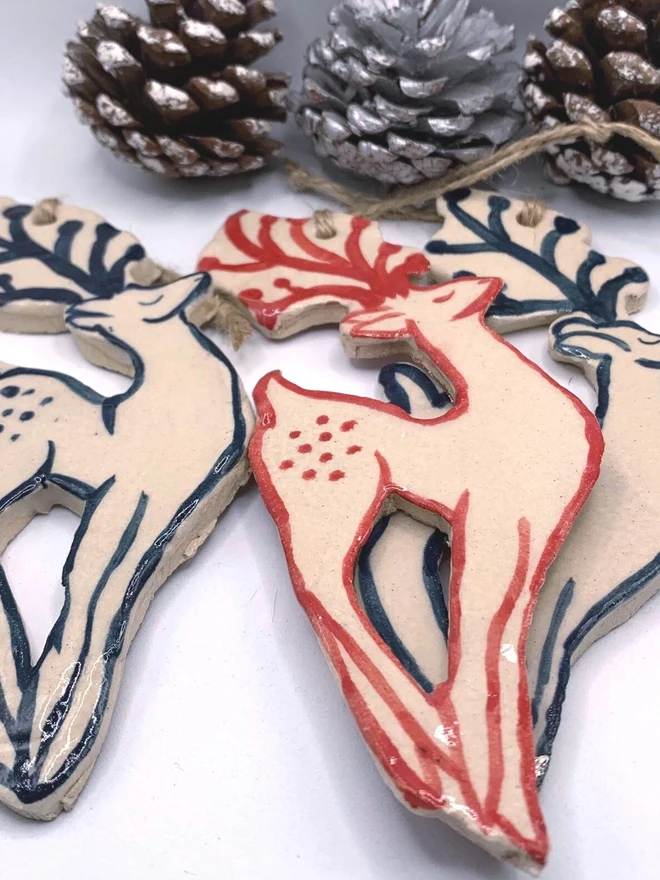 Handmade Ceramic Reindeer Ornament Scandinavian Folk Decor, a group of colourful reindeer decorations sitting on a plain white surface. 
