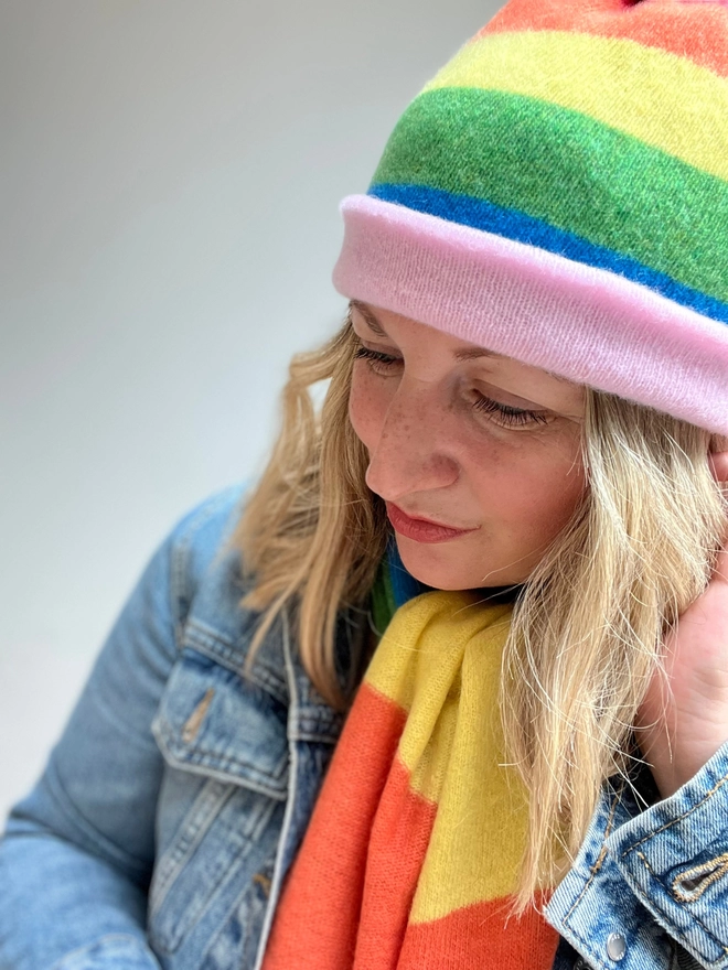 Rainbow striped knitted beanie hat worn with matching scarf