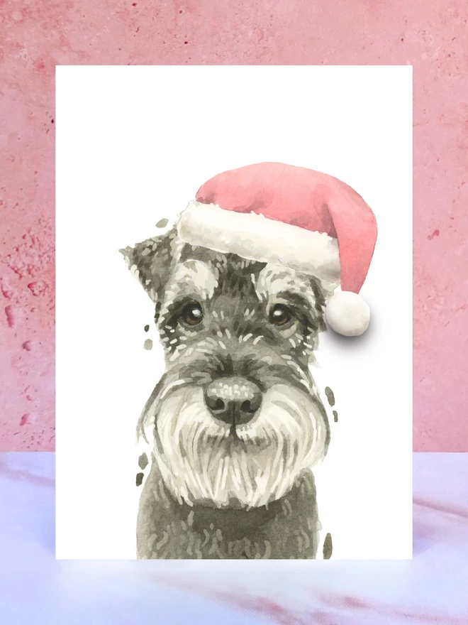 A Christmas card featuring a hand painted design of a schnauzer, stood upright on a marble surface. 