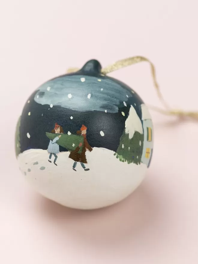 People walking home through the snow hand painted on a Christmas bauble 