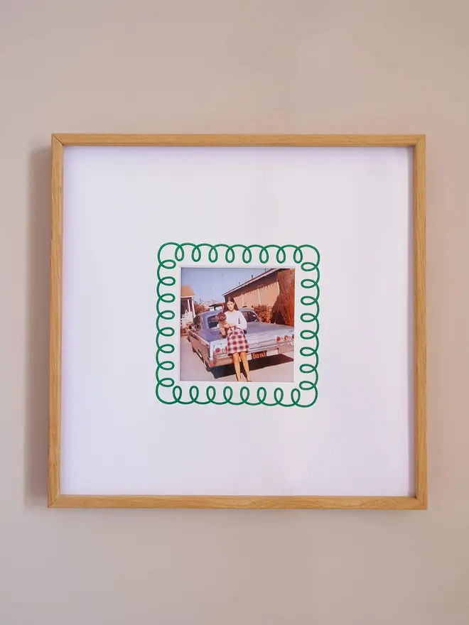 The frill instax square mount frame with a mount featuring a decorative frill border around a centered Instax Square photo, displayed on a neutral beige wall.