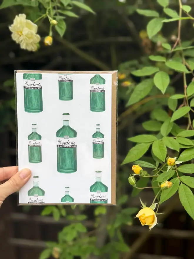 gin bottles illustrated card. card photographed against rosebush backdrop.