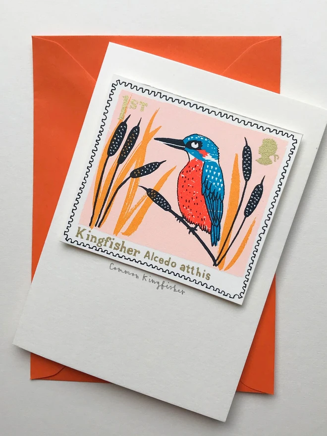 Bird Stamp Card British/ Common Kingfisher Stamp, a white card with a common kingfisher stamp in the centre against an orange envelope on a white background. 