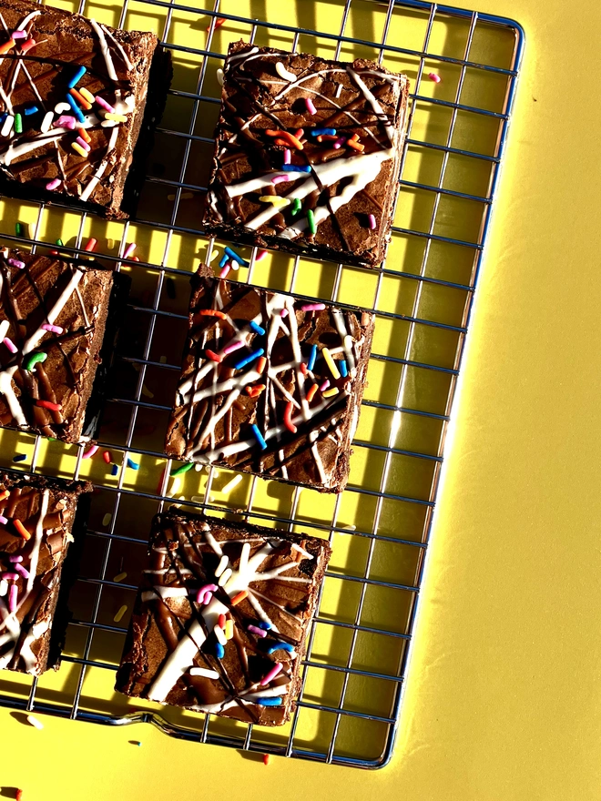 Birthday Brownies Selection (Box Of 6, 12, 16 Or 32), brownies on a baking tray against a yellow backdrop. 