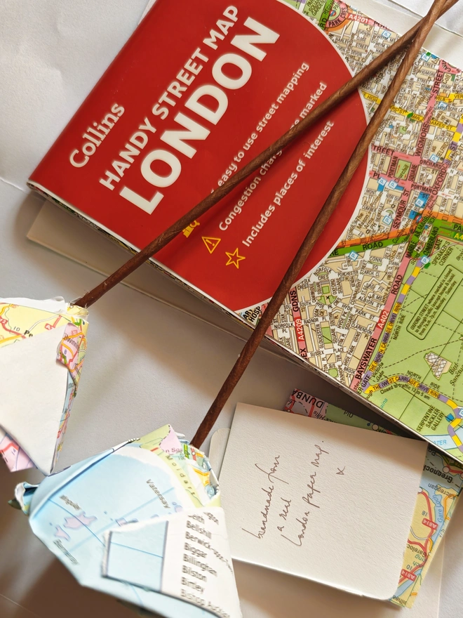 Real Paper Map Roses - Custom Destination. a map of london on a desk.