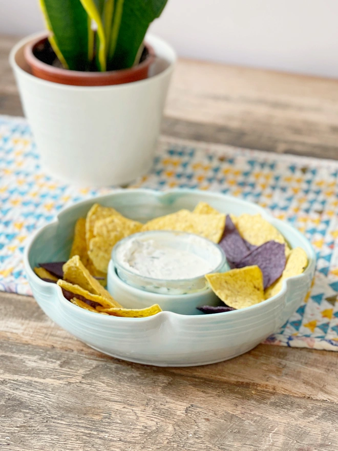 flower shaped chip and dip bowl on a rustic wooden table with tortilla chips and dip