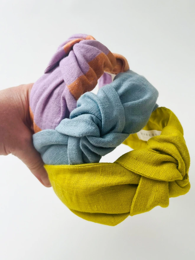 Three chic womens headbands being held to show top knot