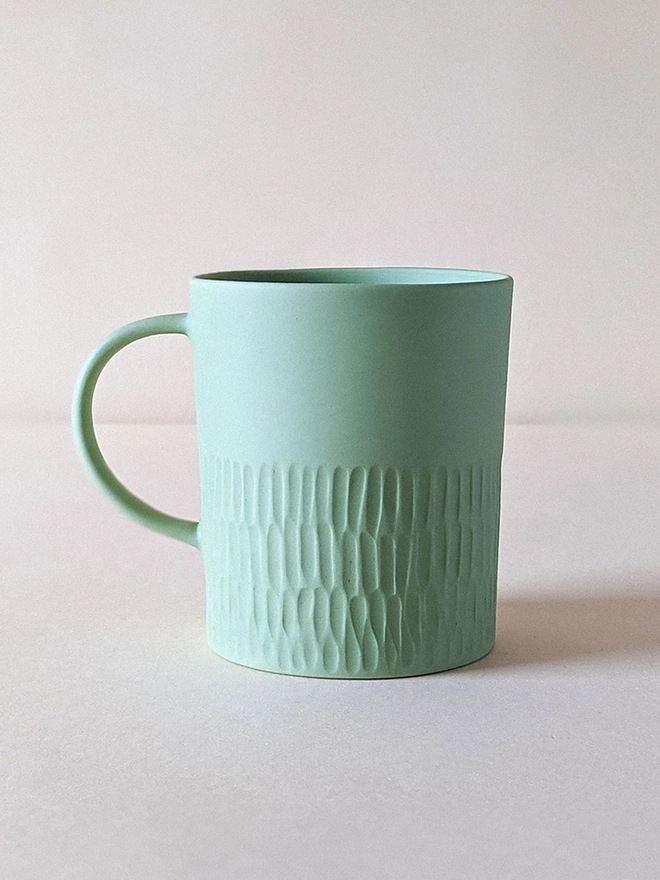 Large Morning Tea Mug made of porcelain in a Pale Rockpool Green with hand carved scalloped texture.