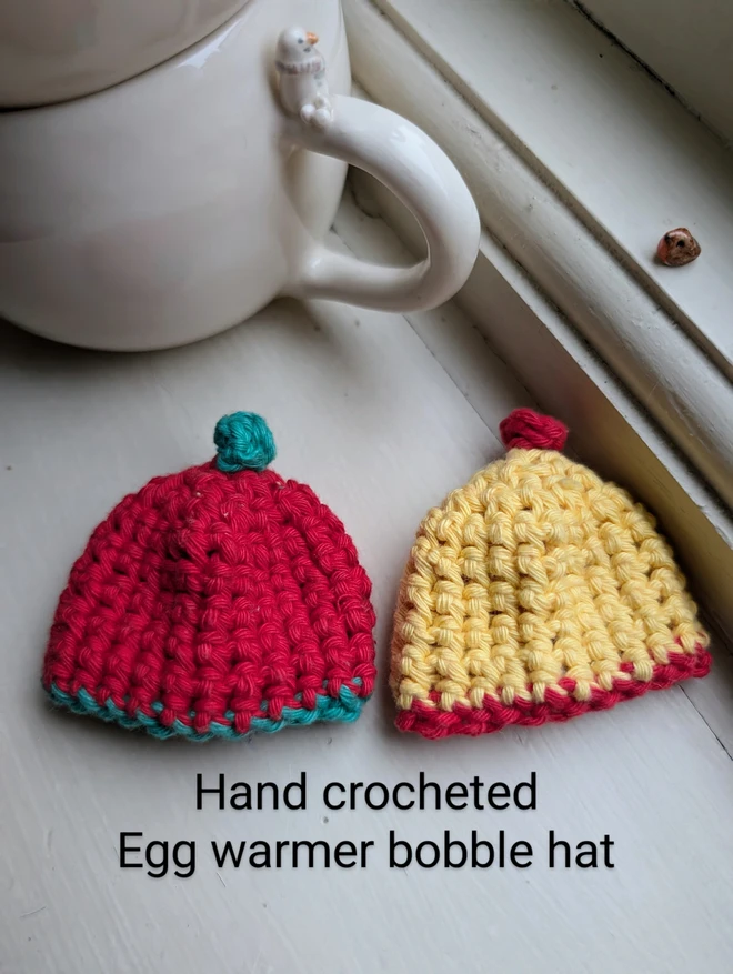 red and yellow hand made little bobble hat for keeping boiled eggs warm laid flat on a windowsill