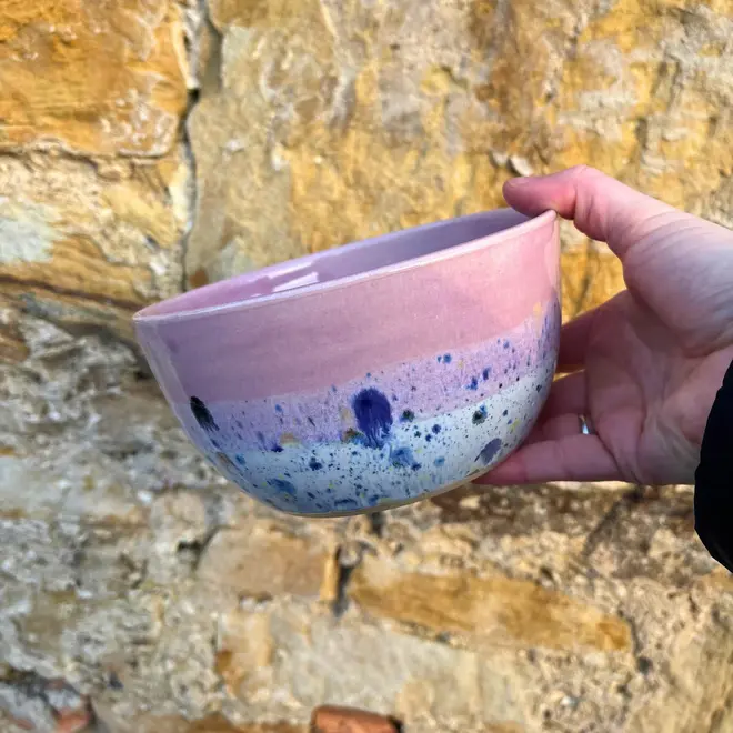 Shoreline Ramen Bowl, a person holding a colourful ramen bowl against a brick backdrop. 