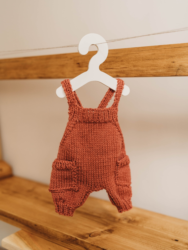 hand knitted personalised red teddy bear dungarees on toy hanger