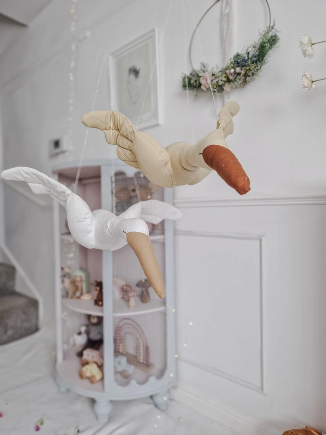 Flying Swan Hanging Decoration, a hanging beige swan decoration, suspended in a child's bedroom. 