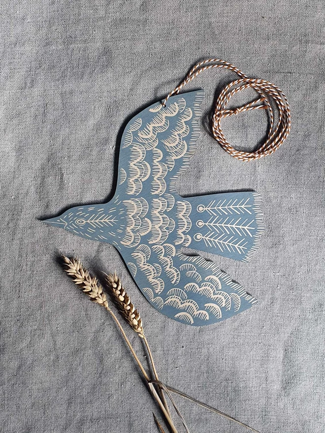 Hanging wooden hand printed bird decoration in a blue grey colour. 